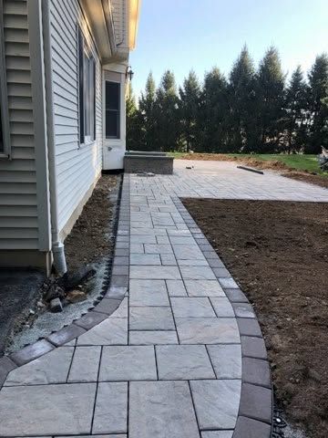 Paver walkway leading to a backyard patio